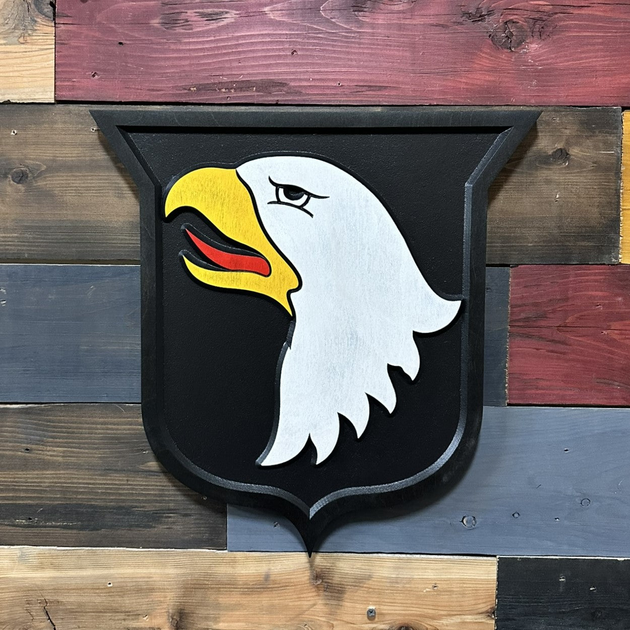 Close up detail of 101st Airborne Division Screaming Eagles carved wood patch showing raised eagle head