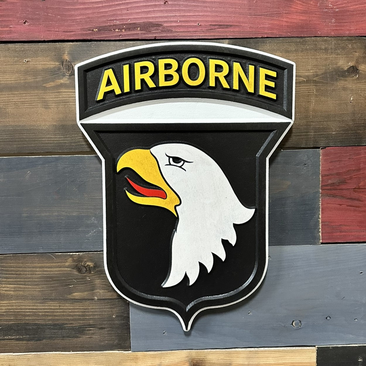 Close up detail of 101st Airborne Division Screaming Eagles carved wood wall sign showing raised eagle head