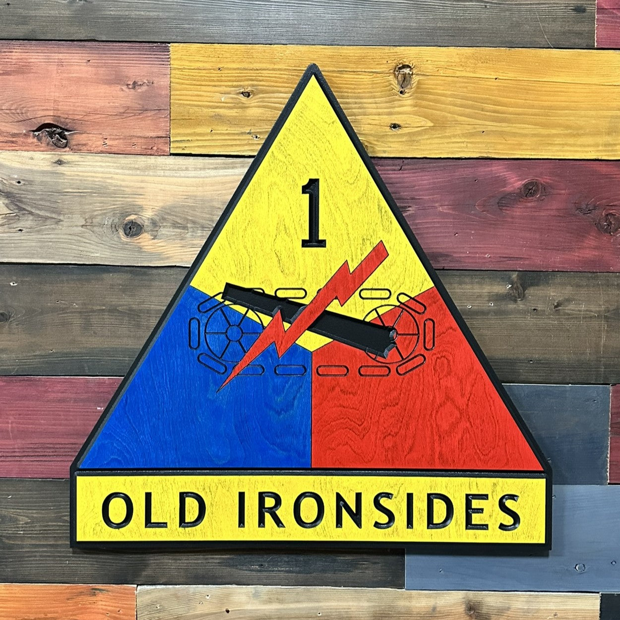 Close up detail of 1st Armored Division Old Ironsides carved wood sign showing dimensional depth and hand painted finish