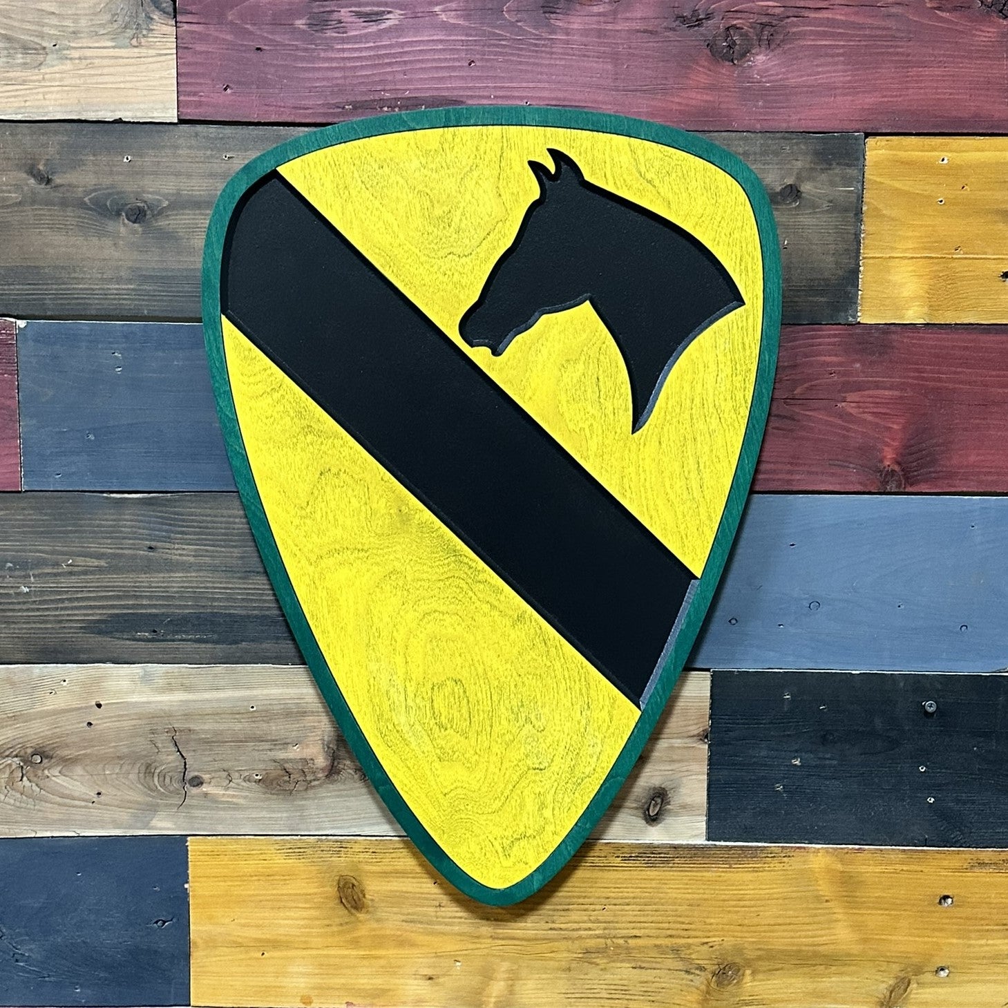 Close up detail of 1st Cavalry Division carved wood sign with green border showing dimensional depth and painted finish