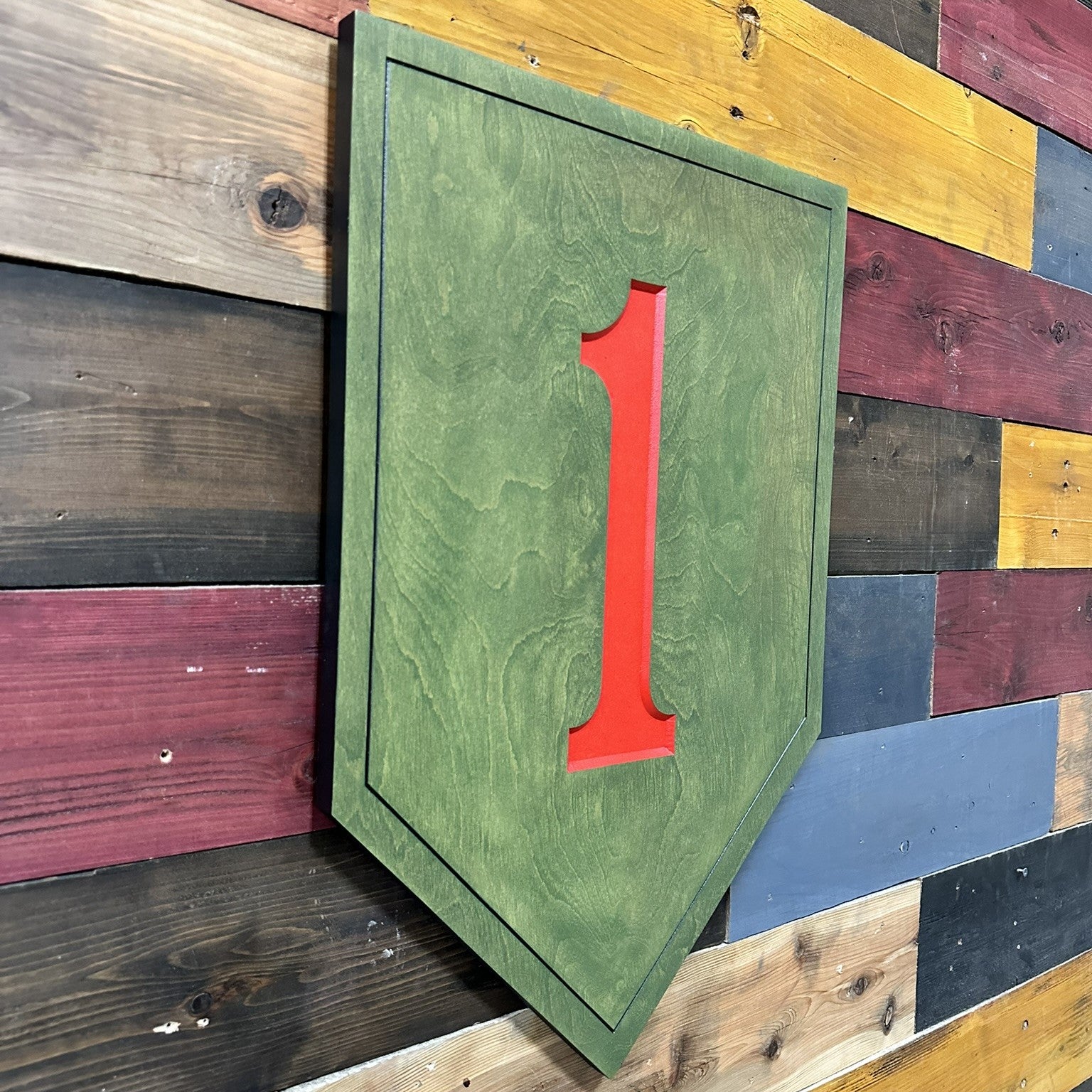 Close up detail of 1st Infantry Division Big Red One carved wood sign showing raised red numeral and green shield