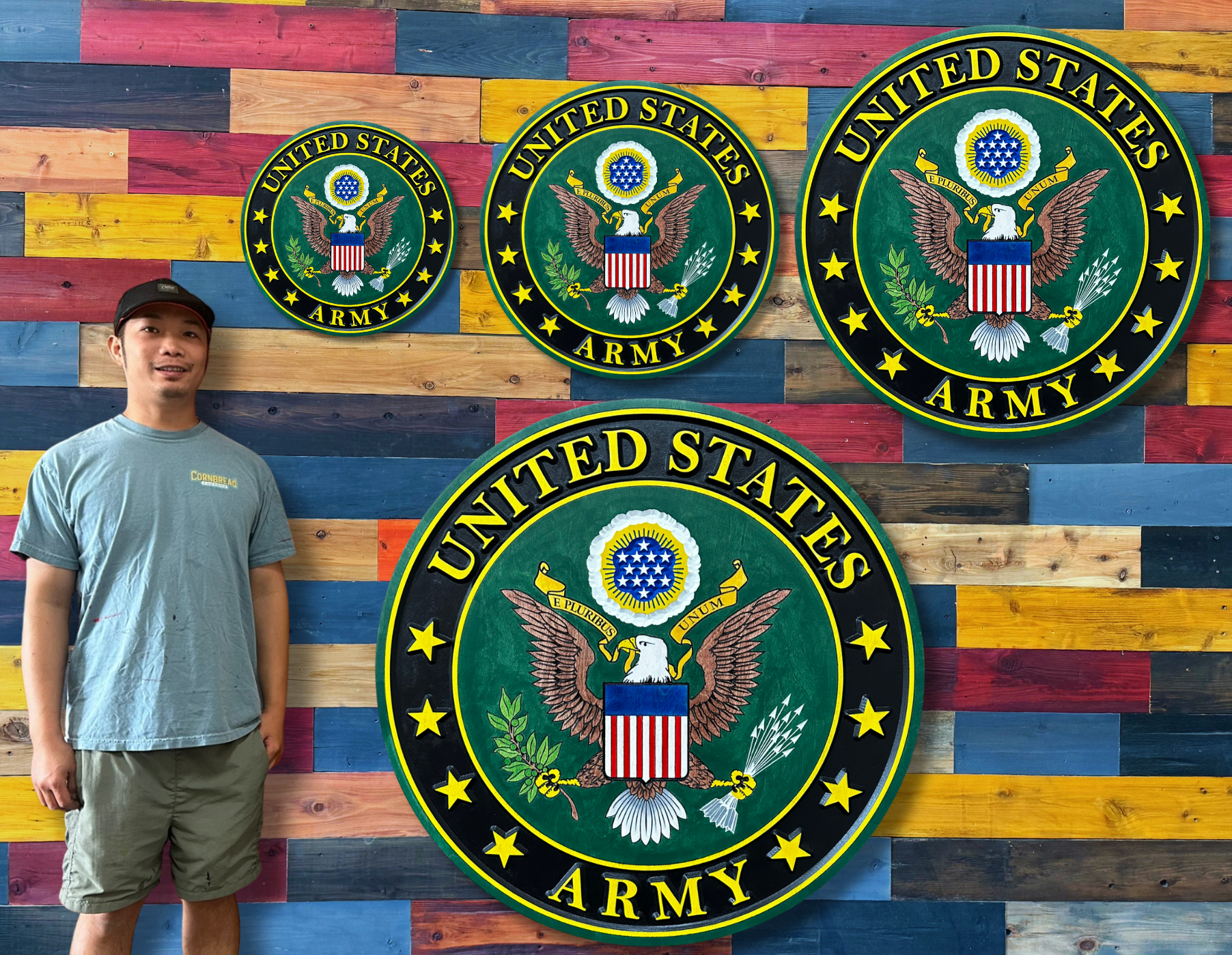 Hoan from Cornbread Custom Signs holding United States Army wood signs in small medium large and extra large sizes for scale comparison