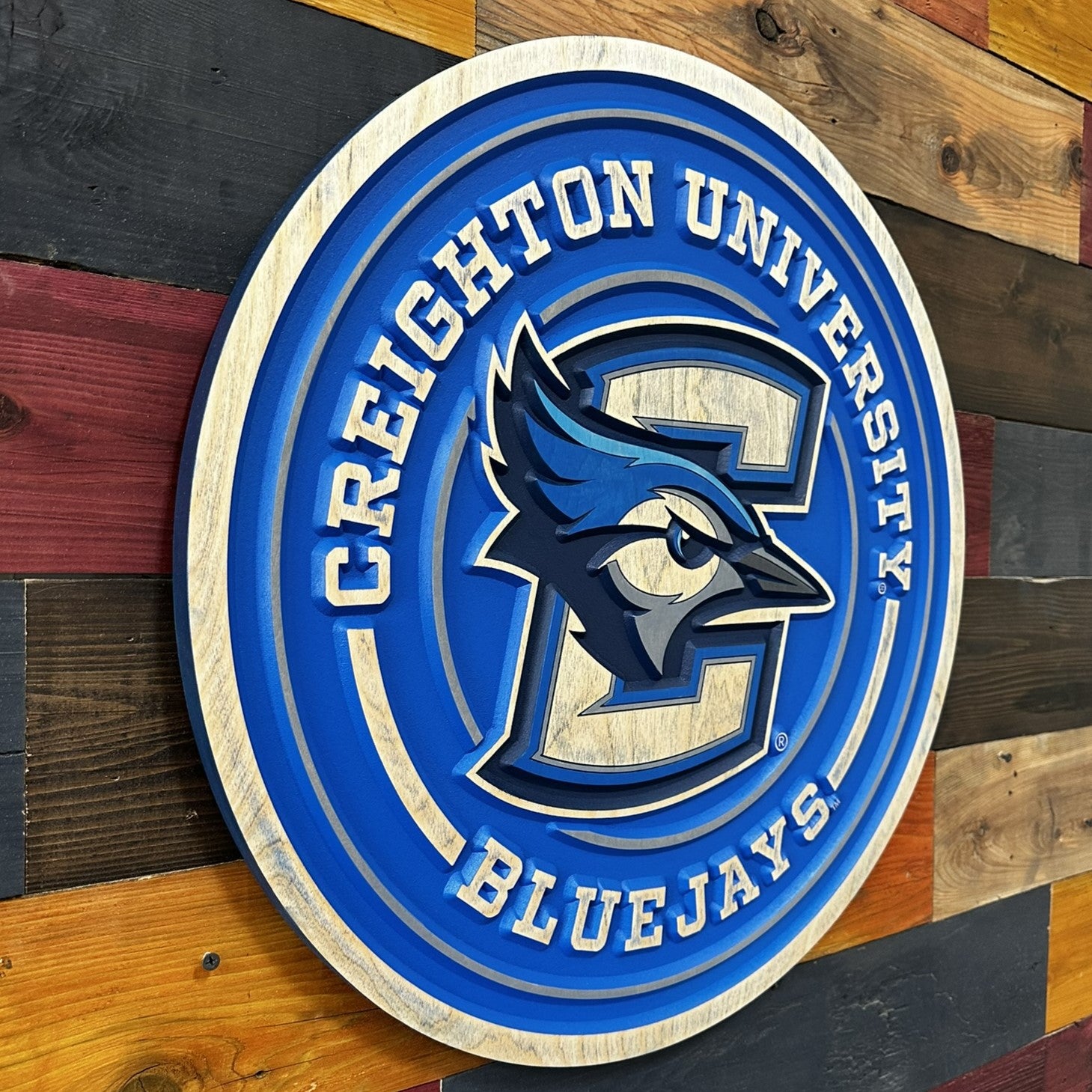 Angled view of Creighton Bluejays round full logo wood sign