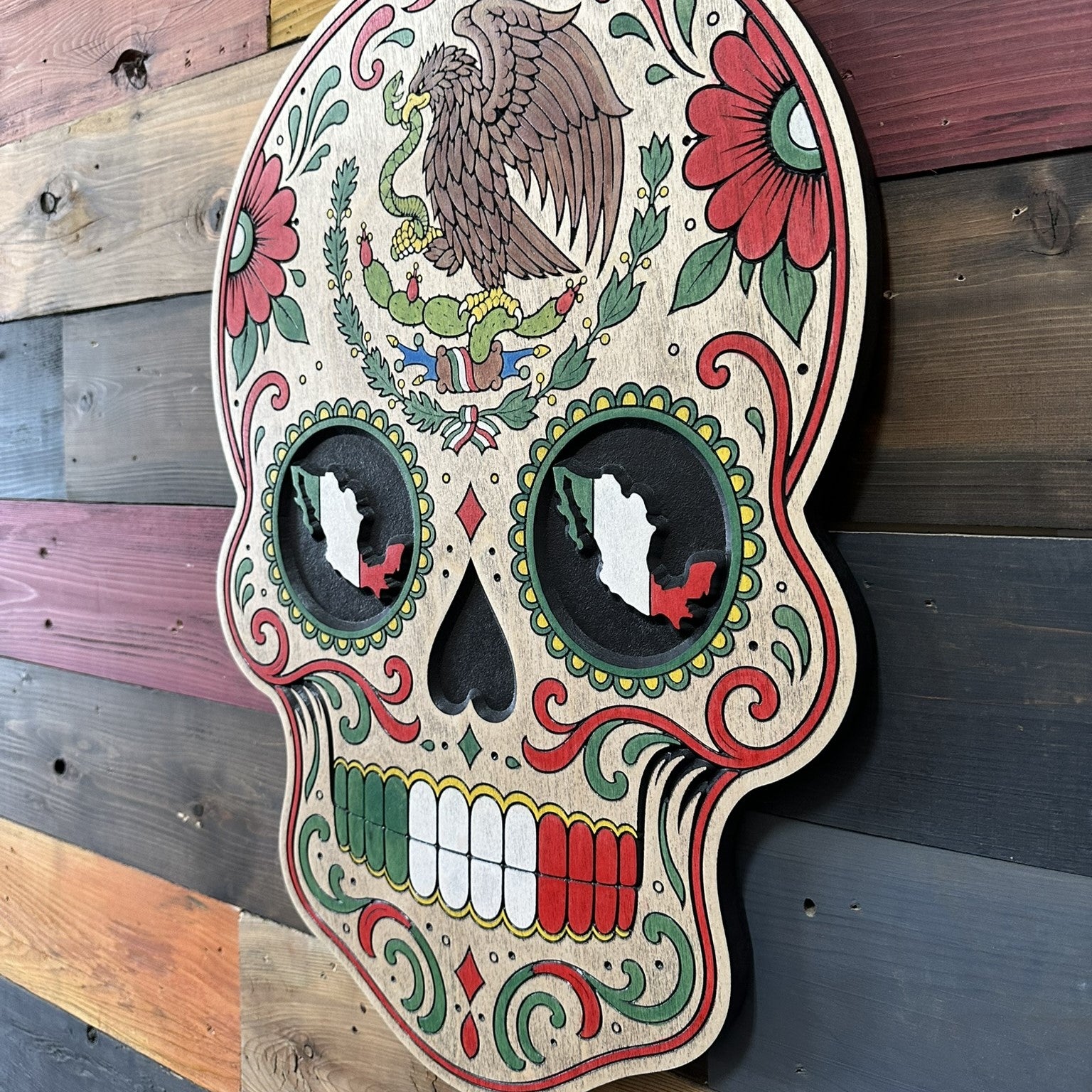 Hand painted Mexican skull wall decor featuring floral folk art, Mexico silhouettes, and red white and green accents