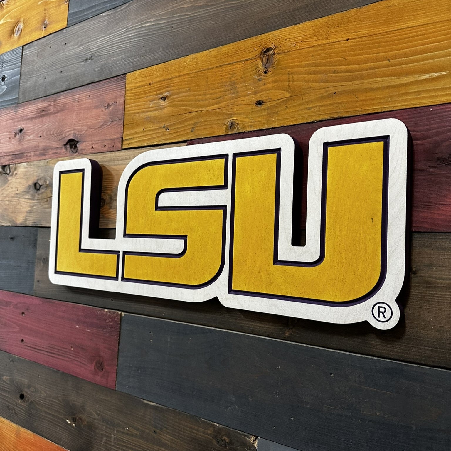 Close up detail of horizontal LSU carved wood lettering featuring layered paint lines and beveled dimensional texture