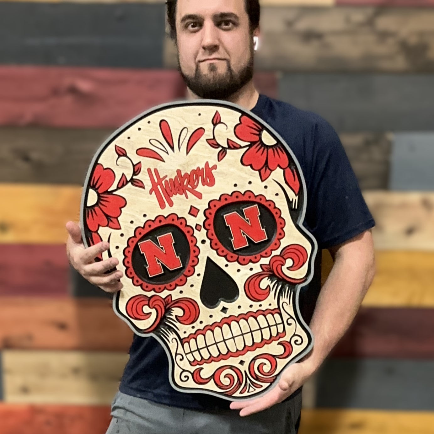 Huskers sugar skull wood sign being held for size reference
