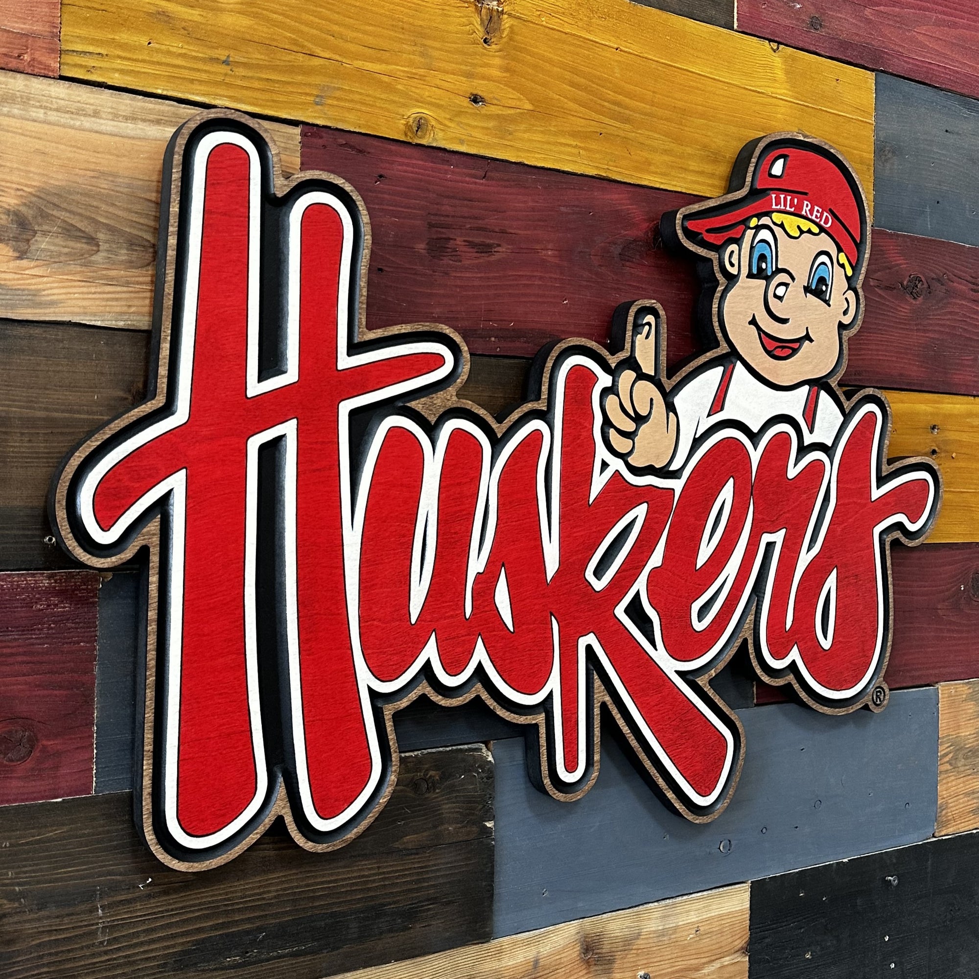 Angled view of Lil’ Red cursive Huskers sports wood art