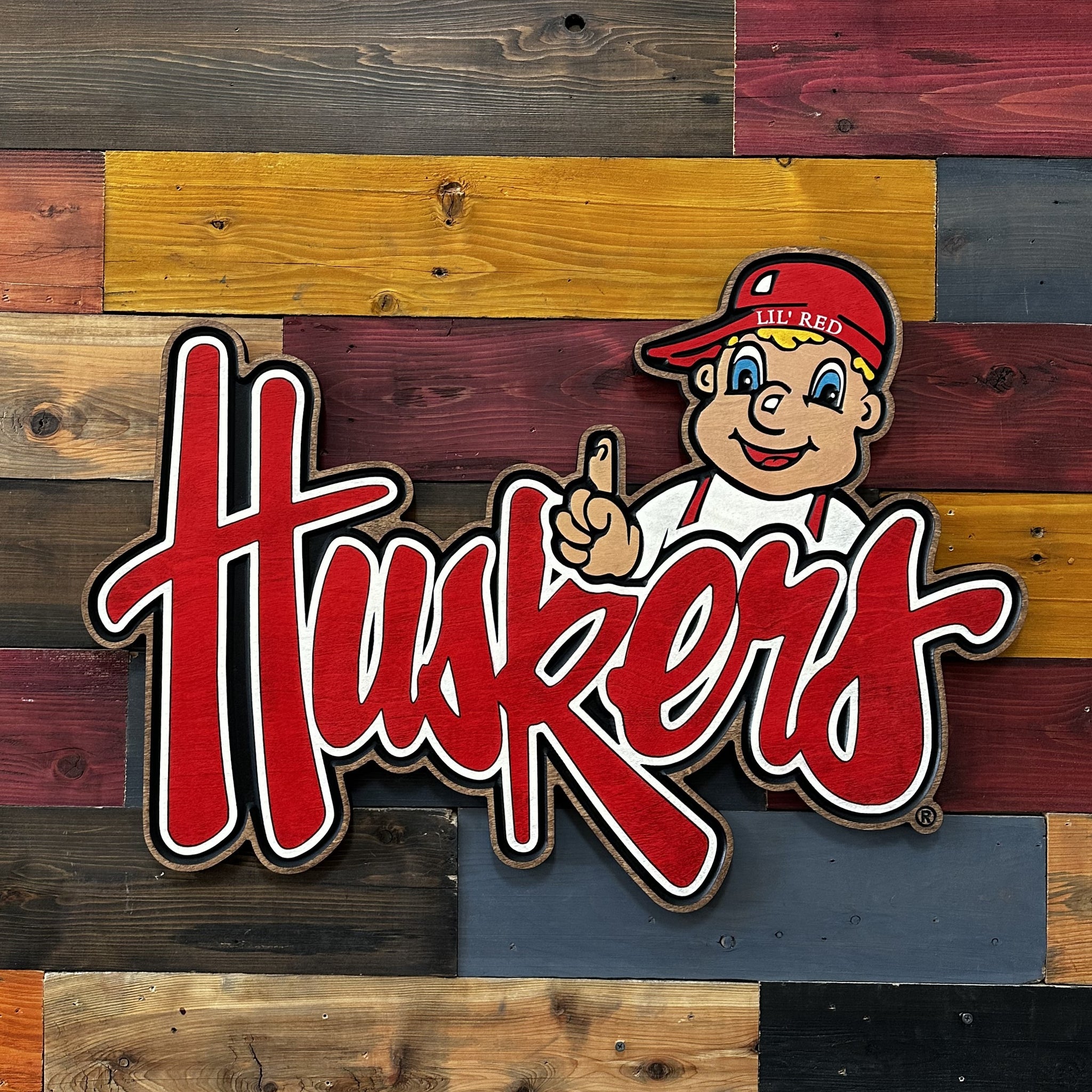 Close-up of carved Lil’ Red cursive Huskers sports wood art detail