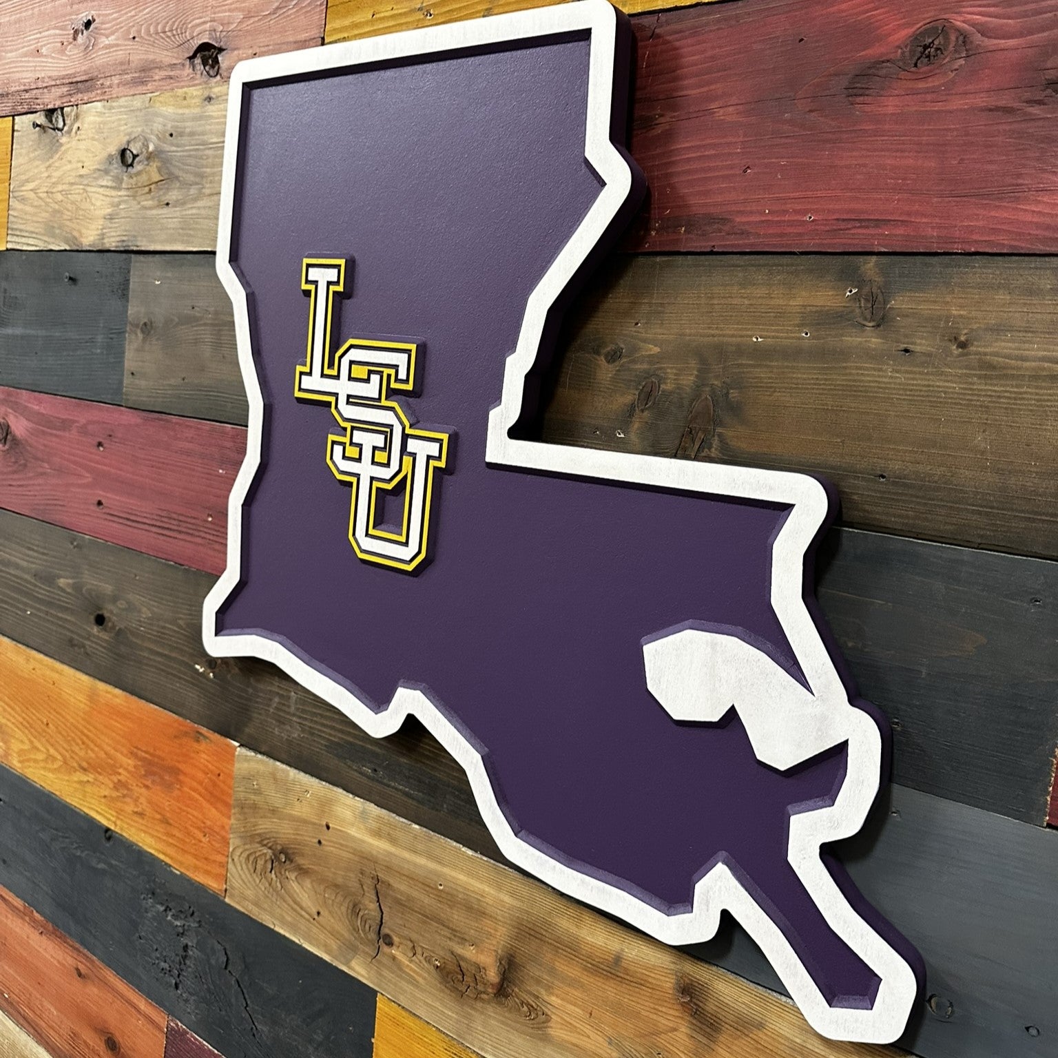 Close up detail of LSU collegiate lettering centered inside a carved Louisiana state silhouette with layered dimensional texture