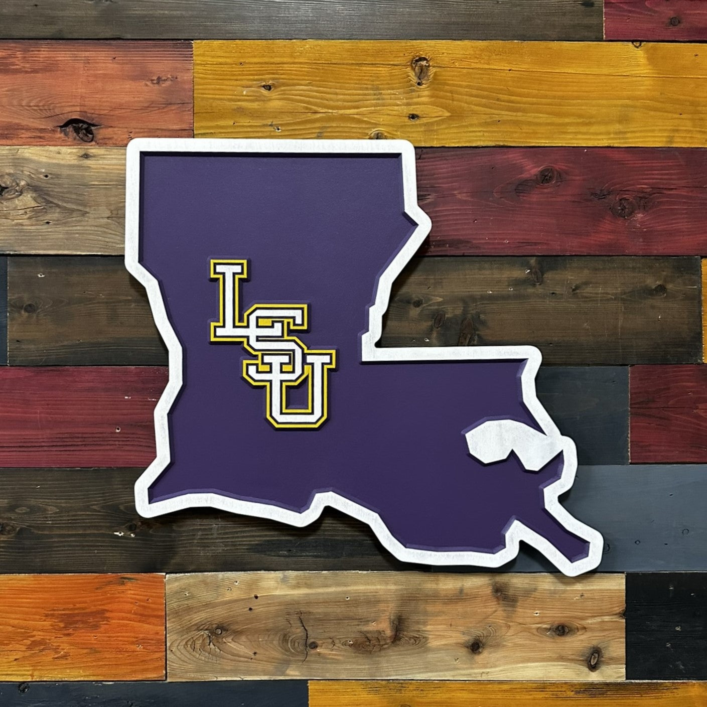 Angled front view of Louisiana shaped LSU wooden wall decor showing dimensional carved detail and bold purple finish