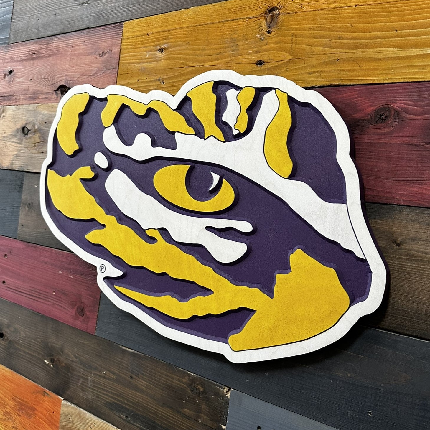 Close up detail of LSU Tiger Eye carved wood artwork featuring layered paint lines and beveled carved texture