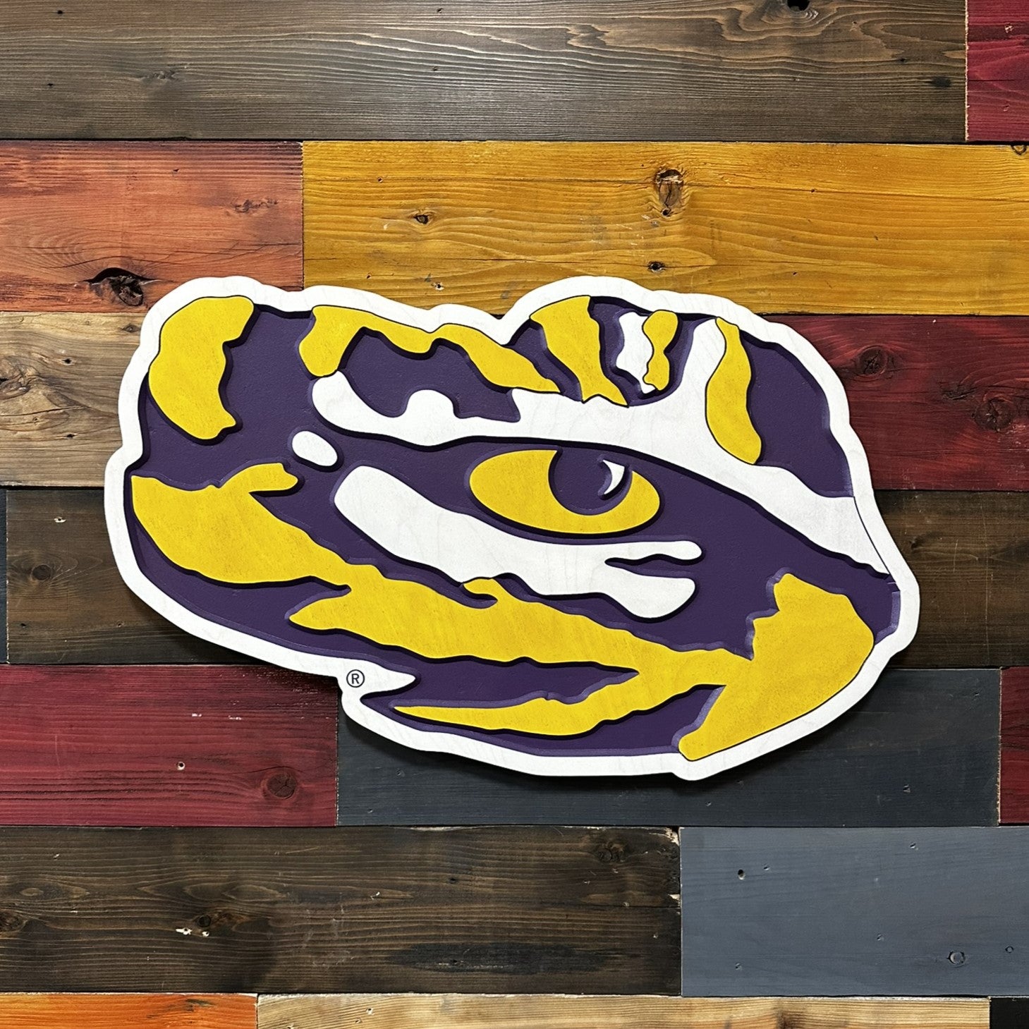 Angled front view of LSU Tiger Eye wooden wall decor showing dimensional carving and bold purple and gold color contrast