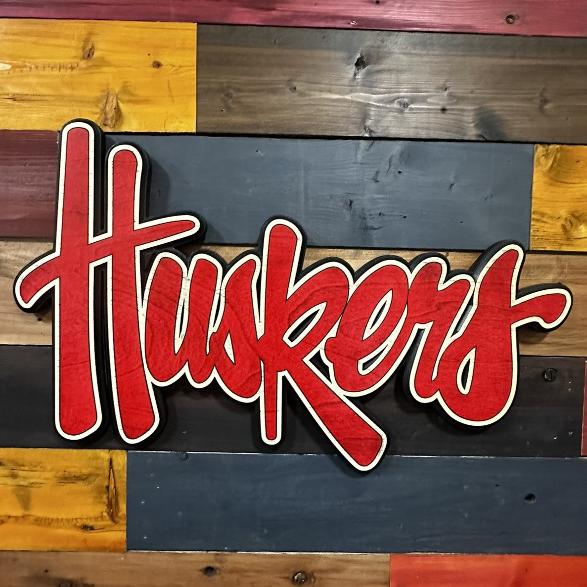 Close-up of Nebraska Huskers red script 3D wood sign detail