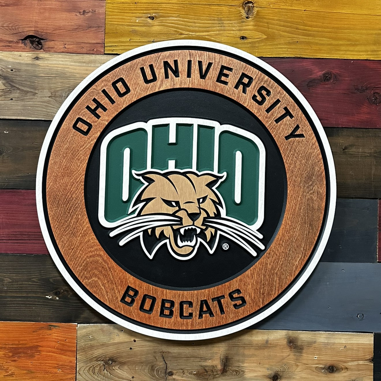 Front angled view of Ohio University Bobcats round wooden wall art showing dimensional carved lettering and natural wood grain border