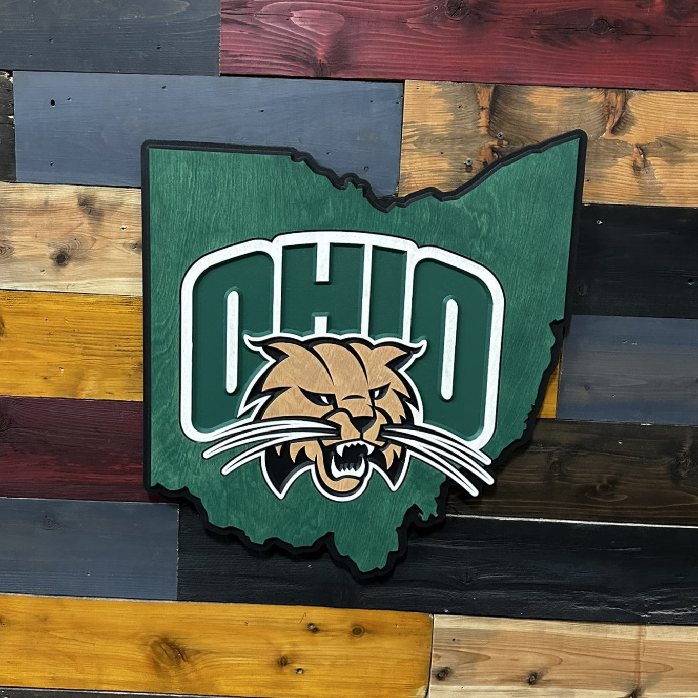 Angled view of Ohio University Ohio state shaped wooden wall decor showing layered carving and stained green wood finish