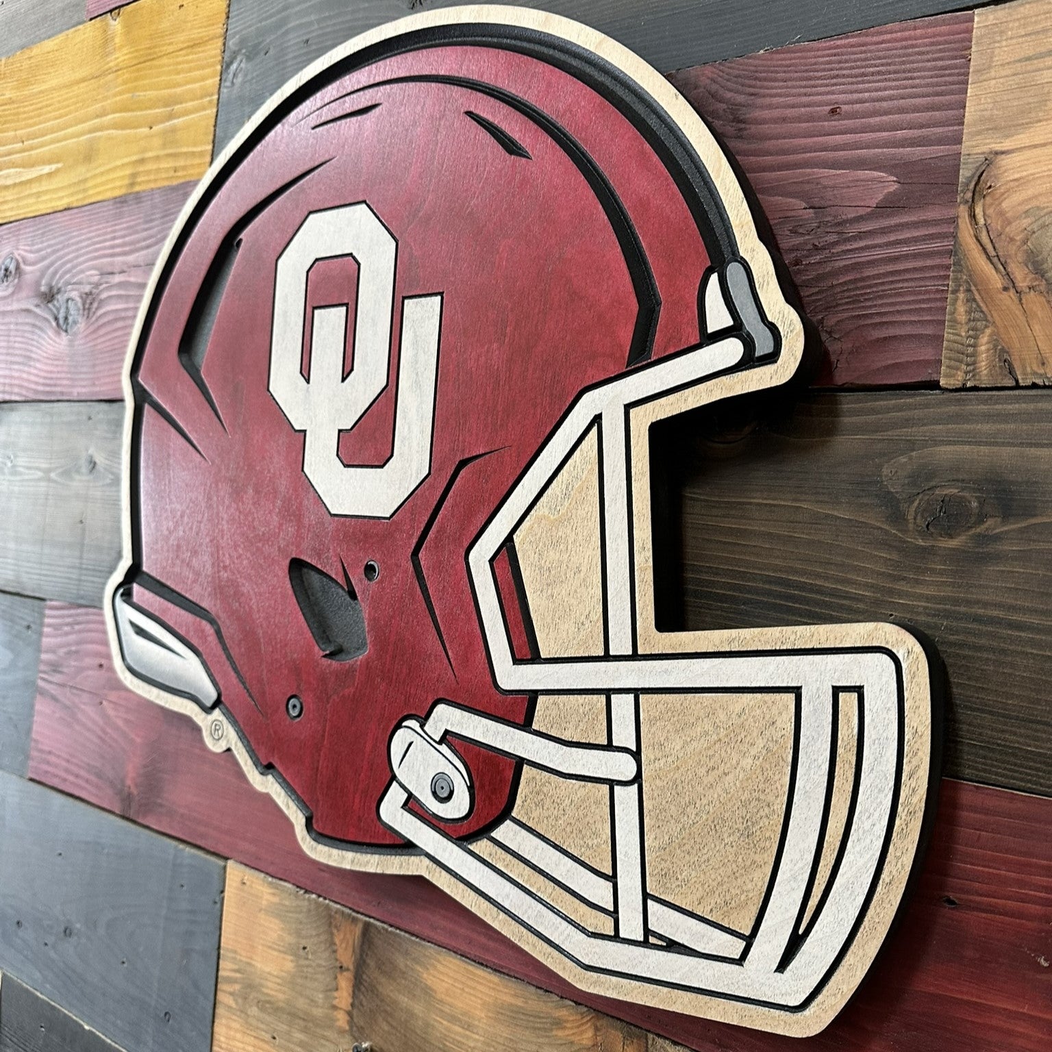 Side angle of the handcrafted Oklahoma Sooners helmet sign showing layered relief carving and painted details.