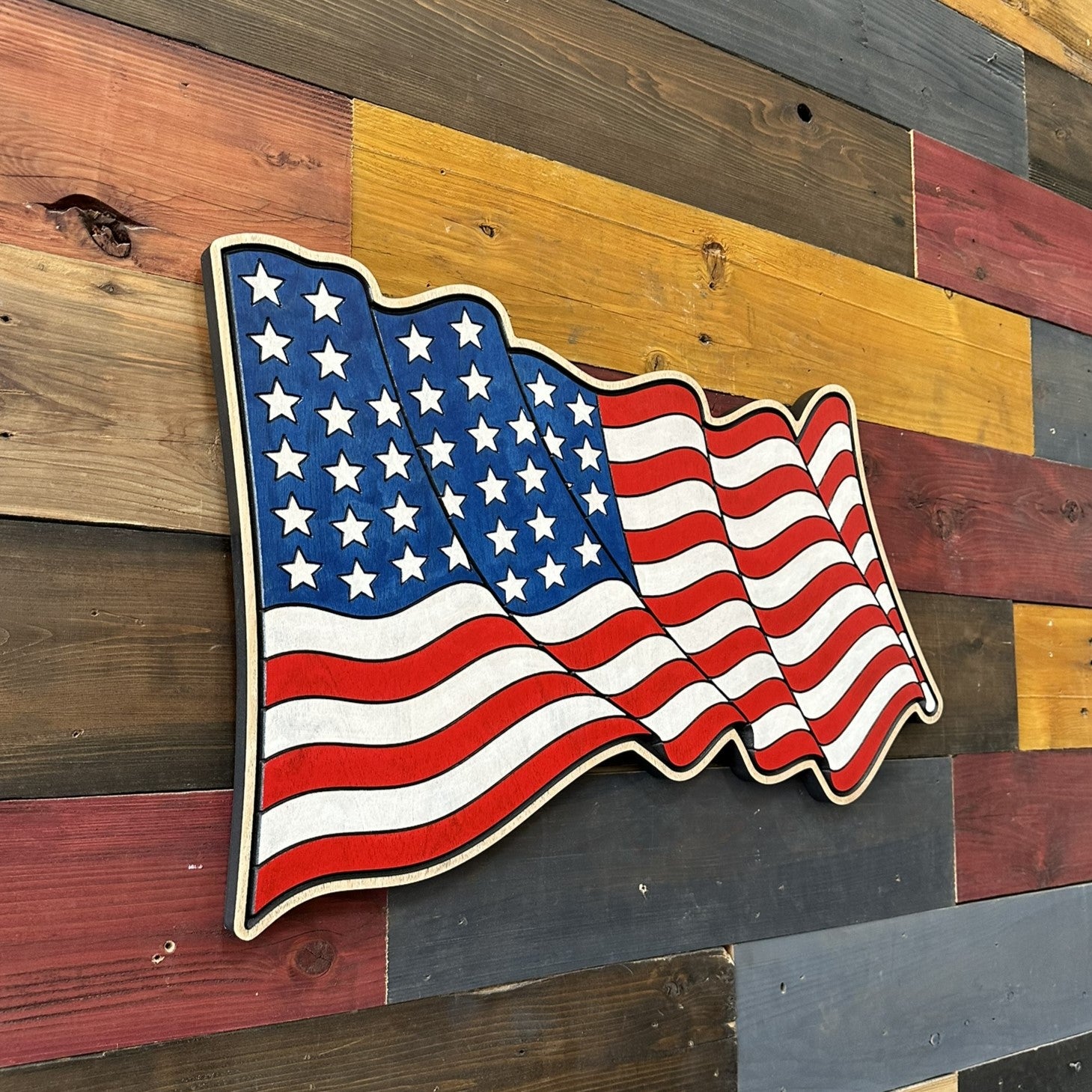 Old Glory patriotic wall decor featuring a carved American flag with flowing red white and blue stripes