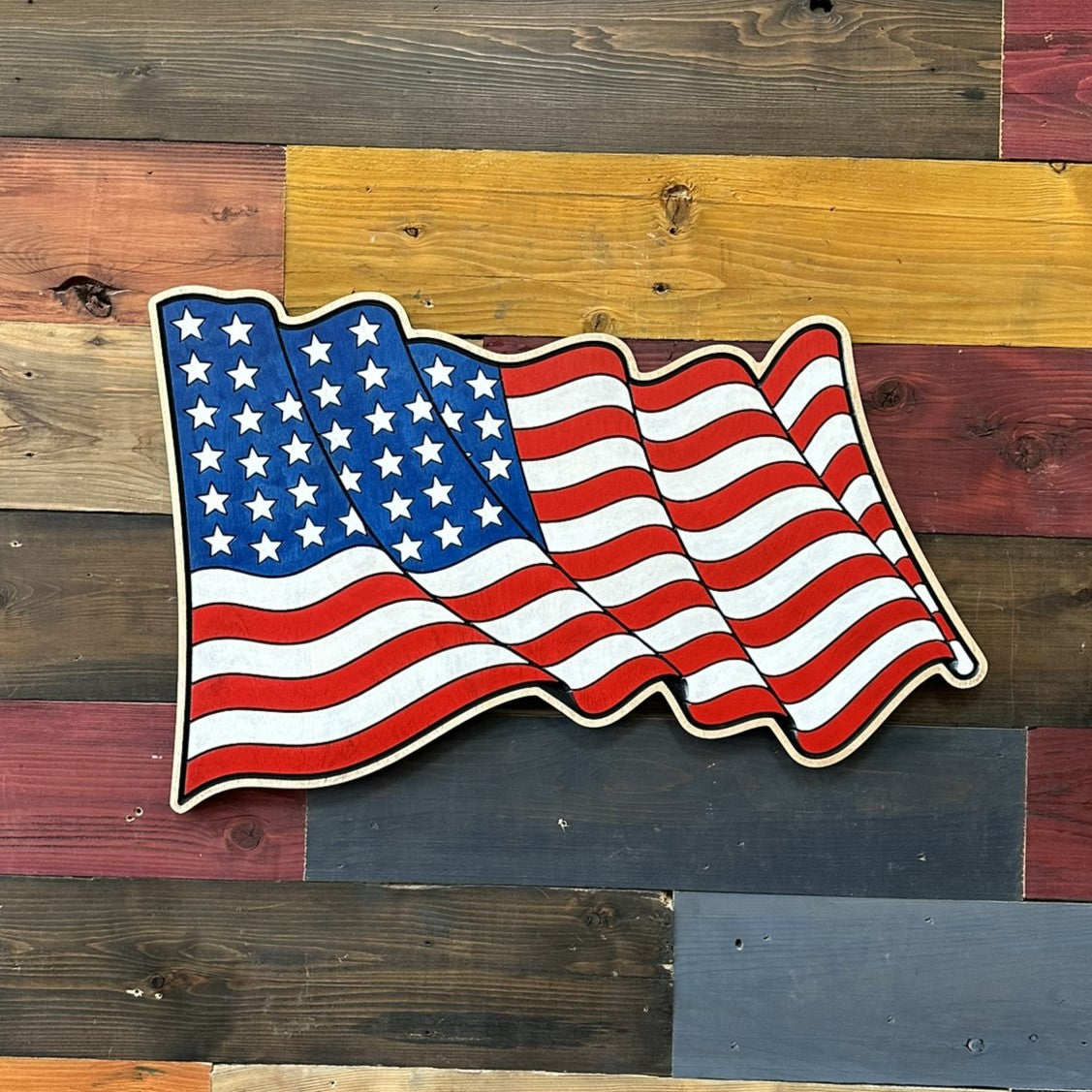 Patriotic American flag wall art featuring a flowing stars and stripes design handcrafted from wood