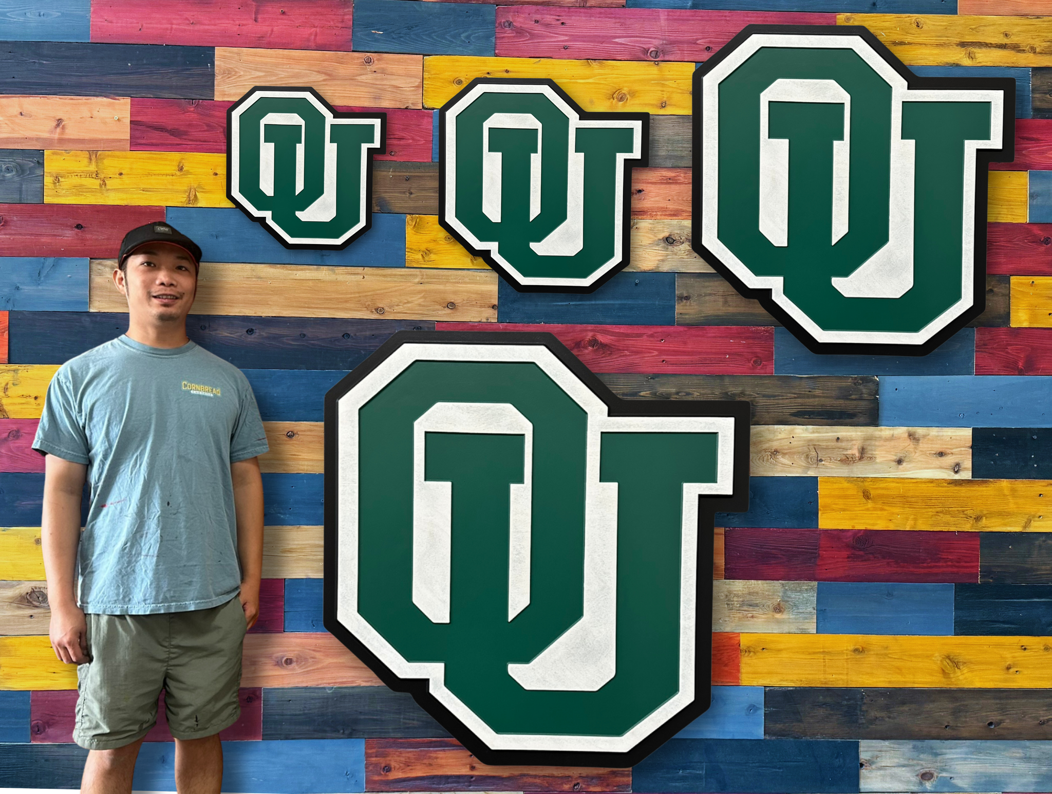 Person standing in front of a colorful wooden wall with large 'OU' logos.