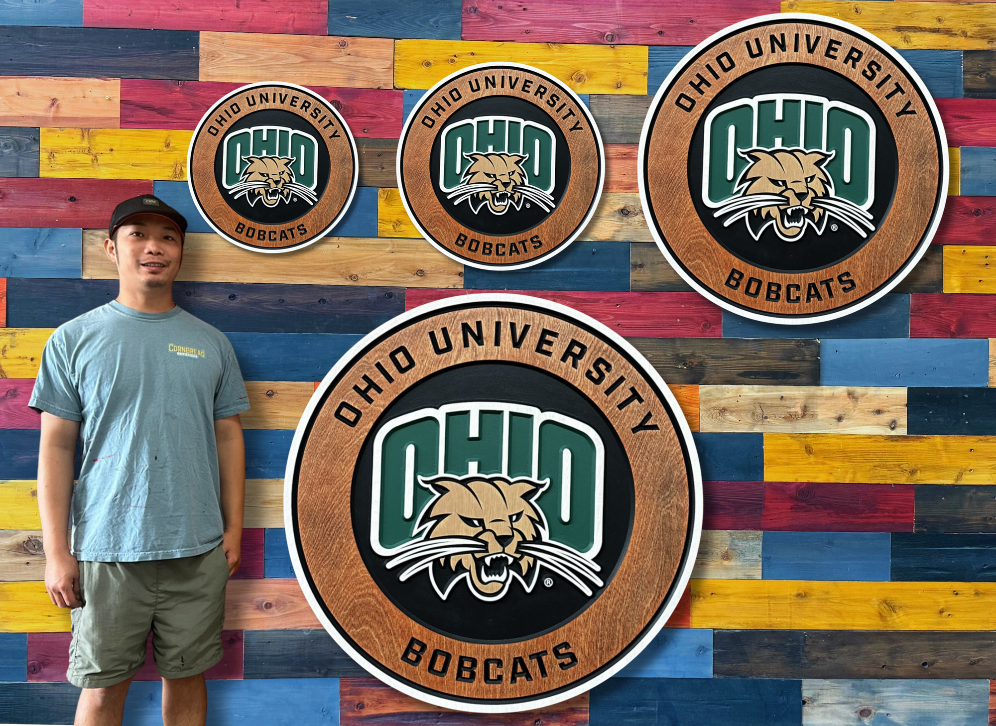 Person standing in front of a colorful wooden wall with Ohio University Bobcats logos.