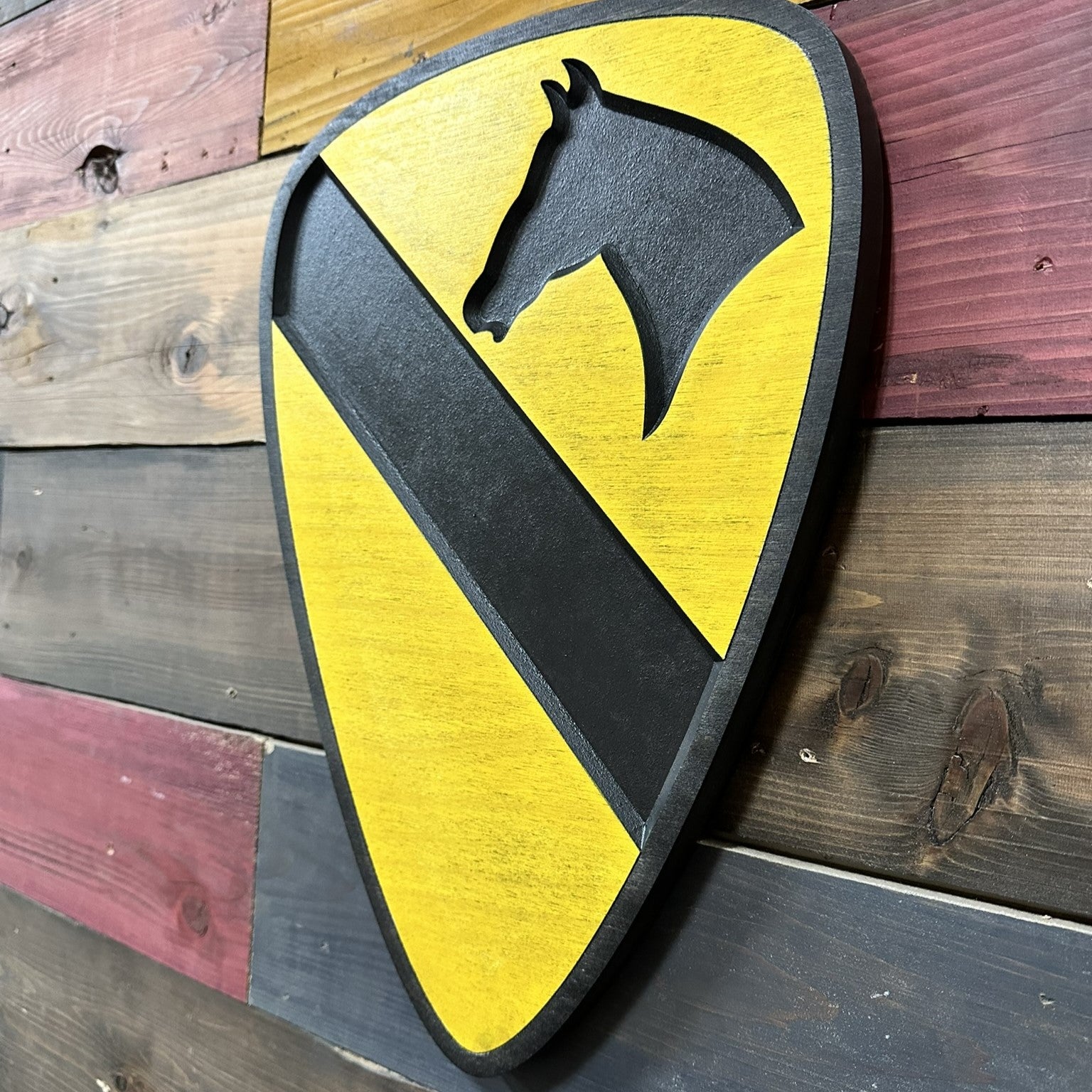 Side profile of US Army 1st Cavalry Division carved wood wall sign with black border showing thickness and carved edge