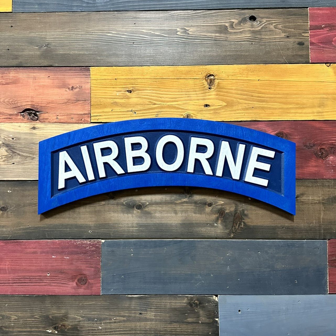 Close up detail of US Army Airborne tab carved wood wall sign showing raised AIRBORNE lettering