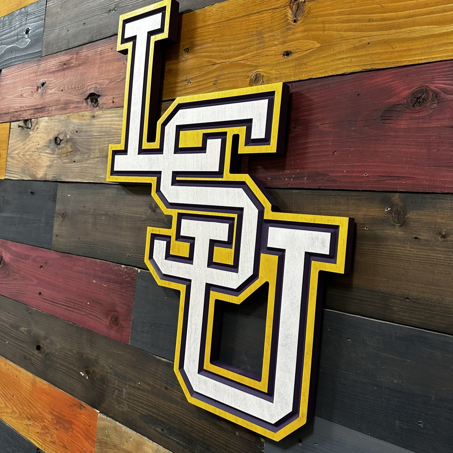 Close up detail of vertical LSU carved wood lettering featuring layered paint lines and beveled dimensional texture
